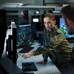 Eine Soldatin zeigt auf einen Monitor und erklärt einem Kameraden die Lage