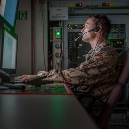 Bundeswehrsoldat mit Headset arbeitet vor einem Monitor