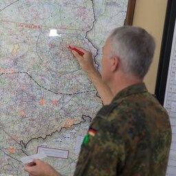 Ein Soldat steht vor einer Landkarte.