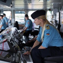 Eine Soldatin beobachtet die Navigationsmonitore auf der Brücke eines Schiffes.