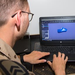 Softwareentwickler in Uniform arbeitet an einem Laptop