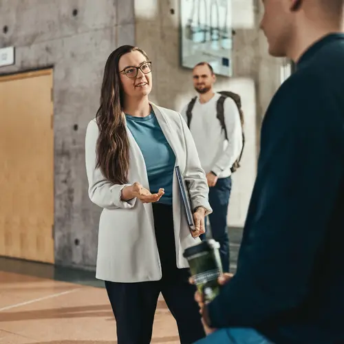 Eine Frau steht in einem Flur und spricht mit einer anderen Person