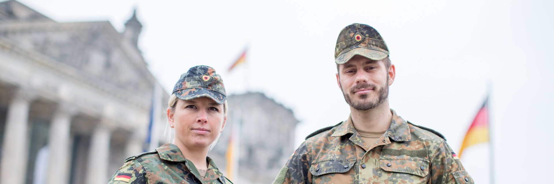 Eine Soldatin und ein Soldat stehen auf der Wiese vor dem Reichstag in Berlin
