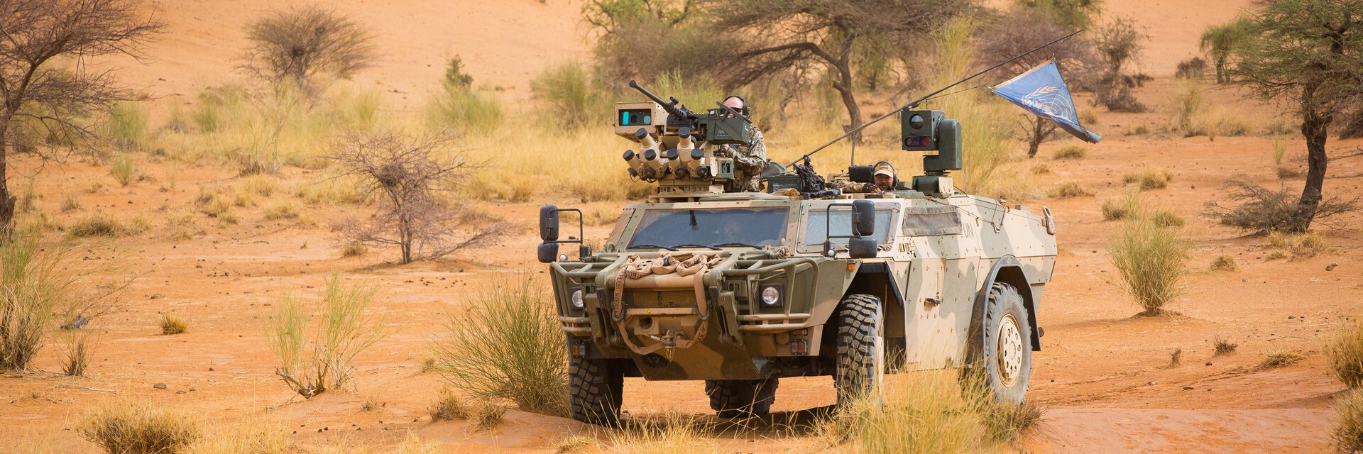 Ein gepanzertes Bundeswehrfahrzeug mit Antennen und Maschinengewehr steht im GelÃ¤nde