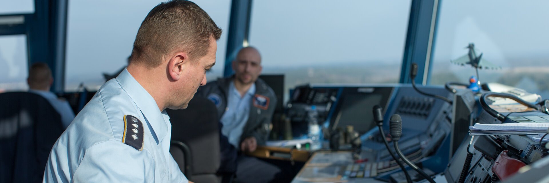 Fluglotse in Uniform sitzt im Tower eines Flugplatzes und koordiniert die Flugbewegungen.
