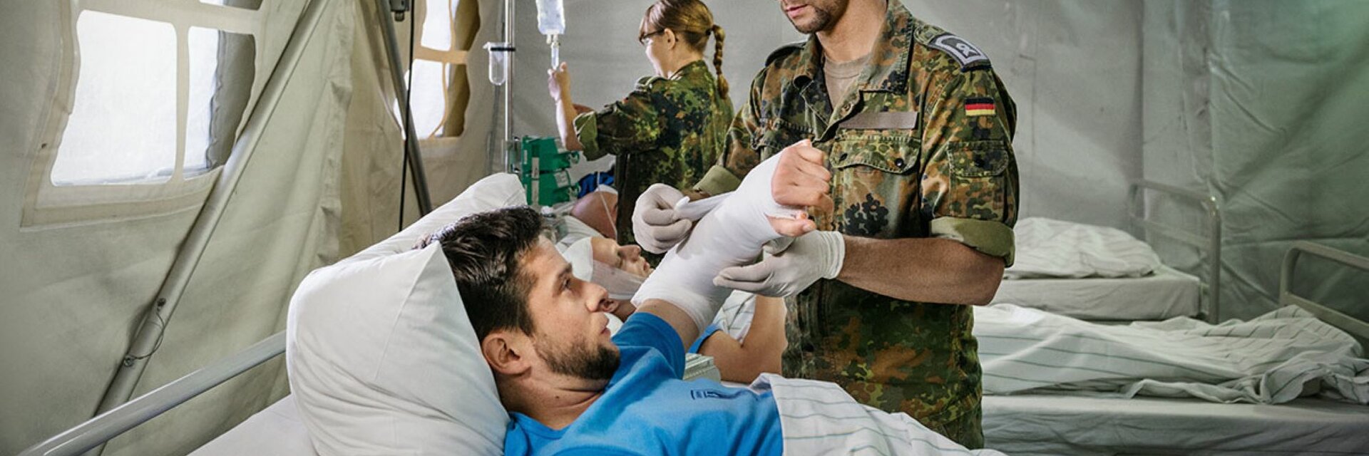 Ein SanitÃ¤tsunteroffizier und Pflegefachmann verbindet einem Verwundeten den linken Arm