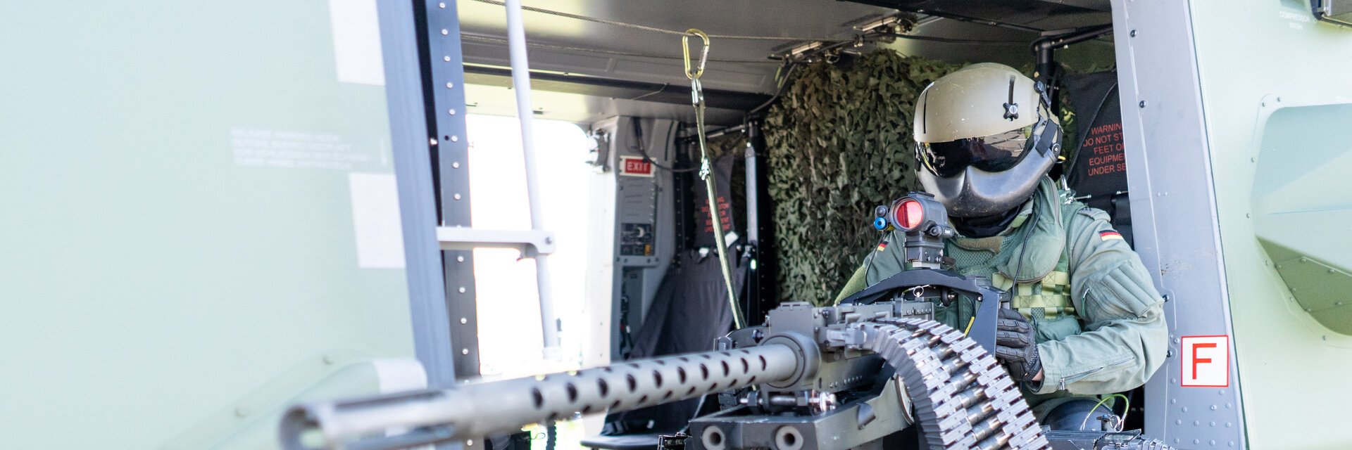 BordschÃ¼tze in Uniform sitzt mit Maschinengewehr in der SeitentÃ¼r eines Hubschraubers
