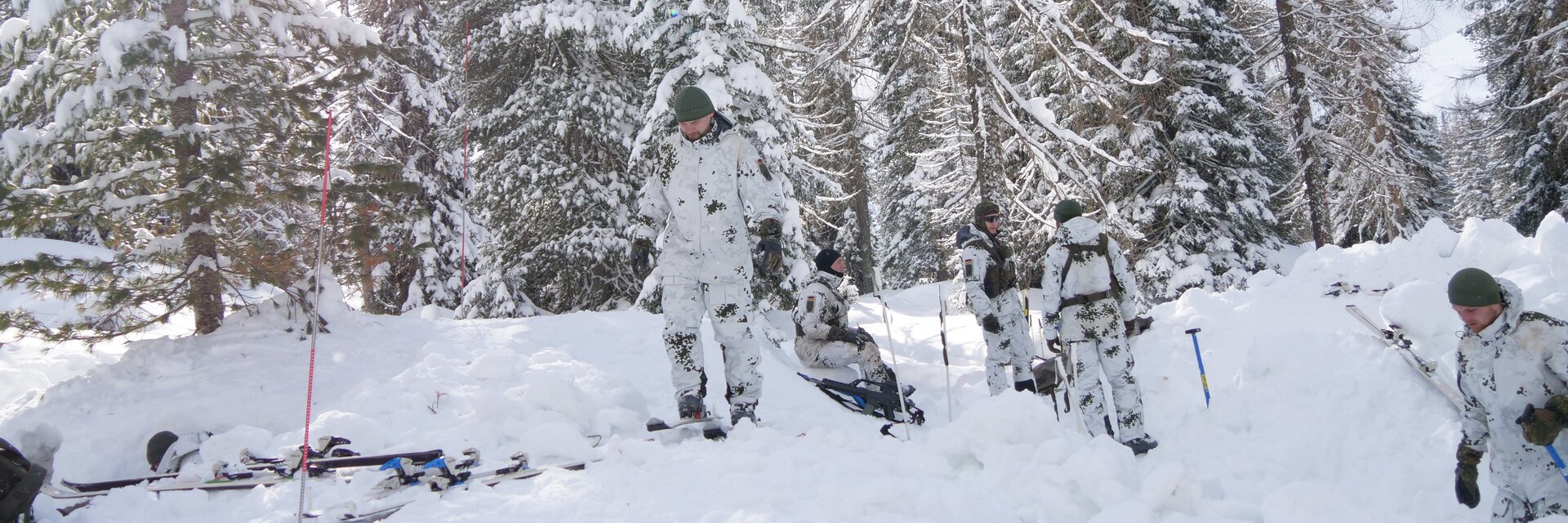 Soldaten der GebirgsjÃ¤gertruppe im Schneetarn-Anzug bereiten ihr Lager im Wald vor.