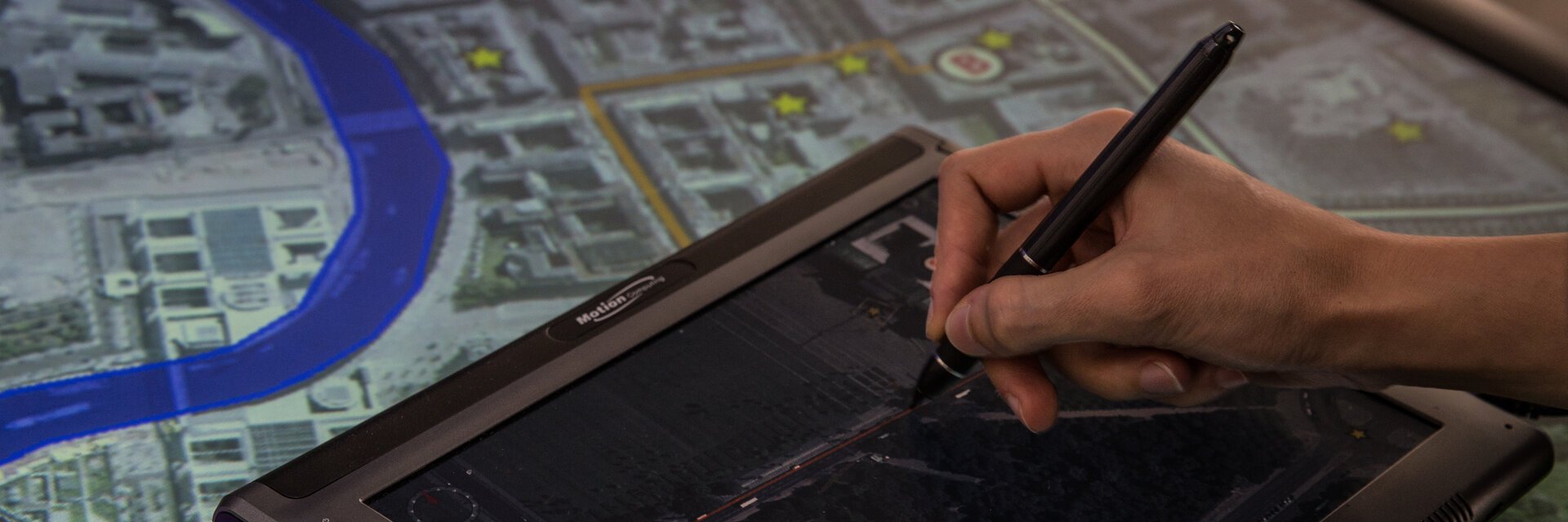 Hand mit elektronischem Pen, die ein Tablet bedient und etwas zeichnet
