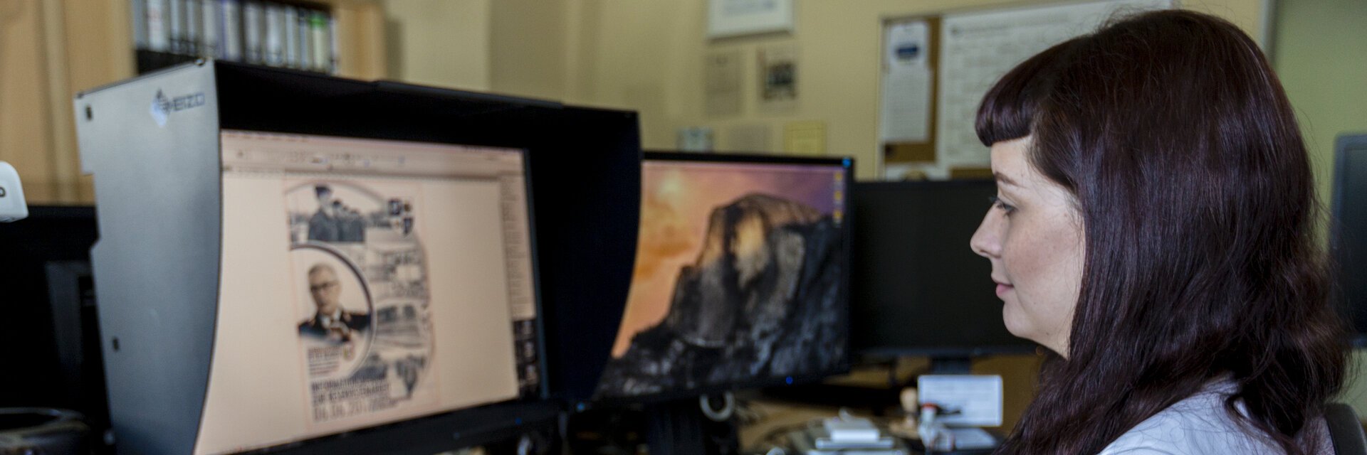 Frau sitzt vor einem Monitor und zeichnet an einem Tablet