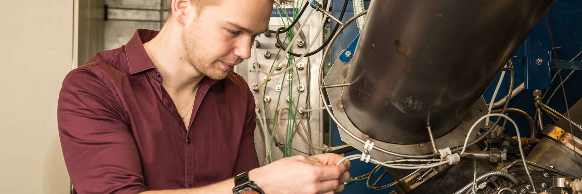 Ein junger Mann arbeitet an einer Maschine mit vielen Kabeln
