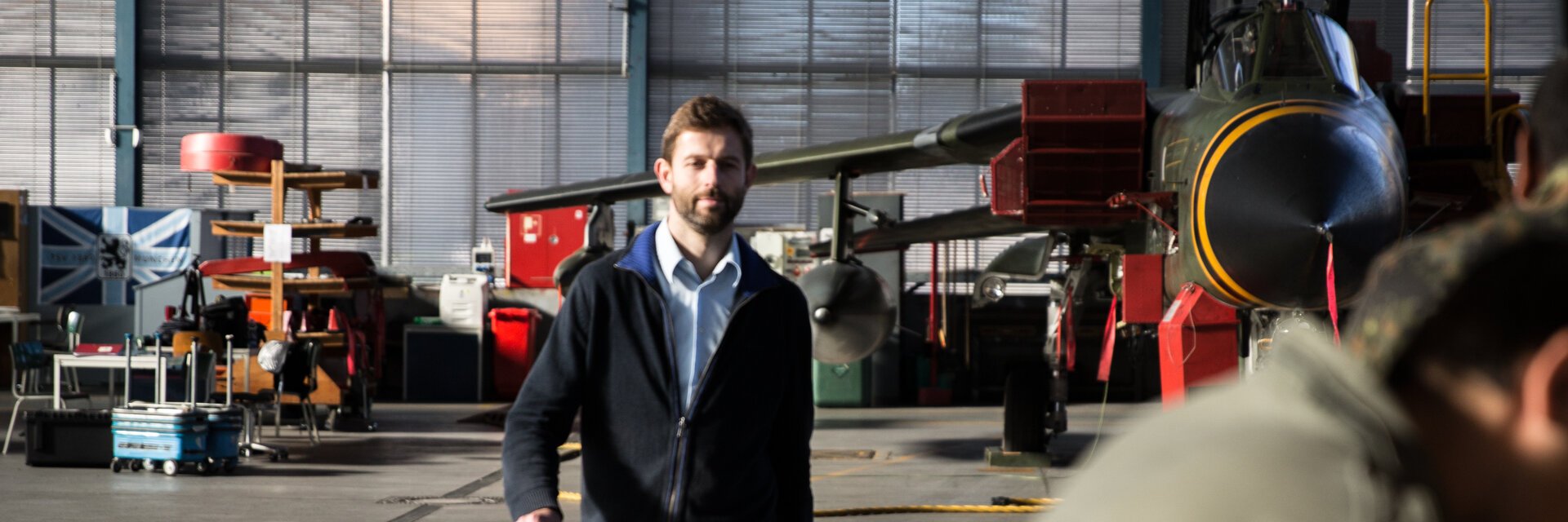 Ein Ingenieur geht durch eine Flugzeughalle zu Mitarbeitern