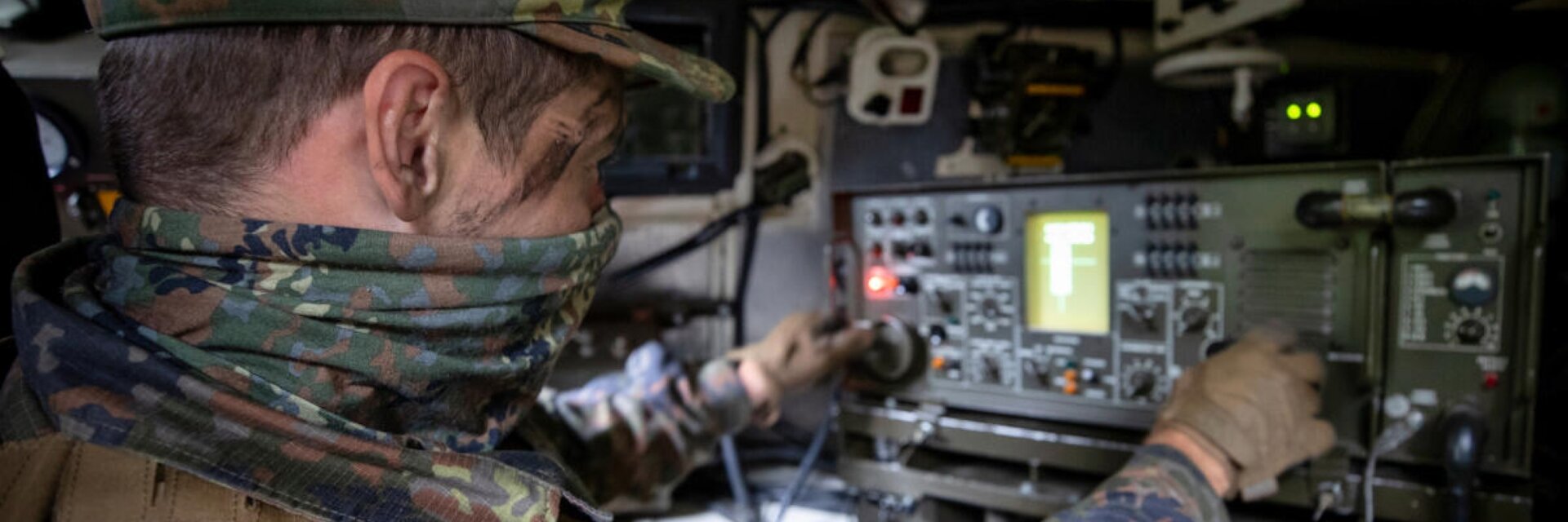 Ein Soldat sitzt in einem gepanzerten Fahrzeug vor einem technischen GerÃ¤t