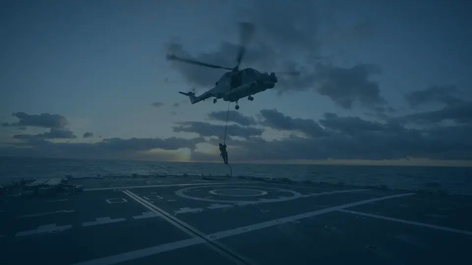 Ein Hubschrauber der Bundeswehr, darunter eine Person, die sich abseilt.