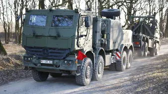 Ein Transportfahrzeug der Bundewehr fährt durch eine Straße im Wald