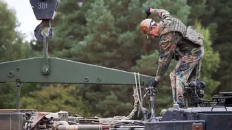 Ein Soldat befästigt Ketten an einem Transporter
