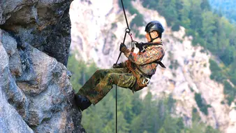 Ein Soldat der Gebirgsjäger seilt sich an einer felswand ab.