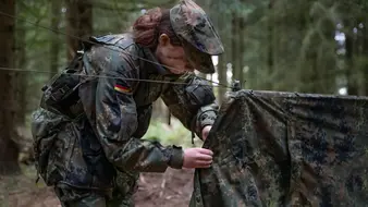 eine Soldatin baut im Wald ein Zelt auf