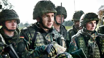 Angehende Offiziere in Flecktarnuniform mit Weste und Helm besprechen die Lage