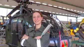 Eine Auszubildende im Bundeswehrkombi steht vor einem Hubschrauber mit einem Drehmomentschlüssel in der Hand