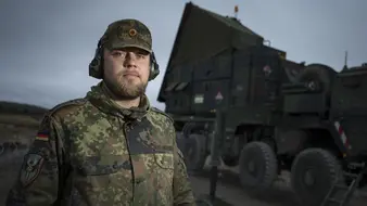 Soldat im Flugabwehrraketendienst steht vor einem großen LKW