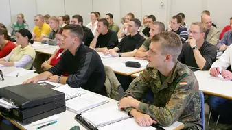 Studenten in Uniform und zivil lauschen einer Vorlesung