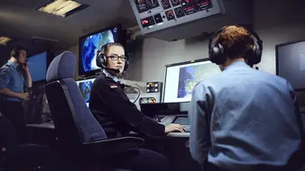 Eine Soldatin der Marine sitzt mit Kopfhörern vor Monitoren.