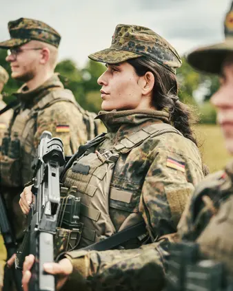 Eine Soldatin steht in einer Reihe mit anderen Soldaten.