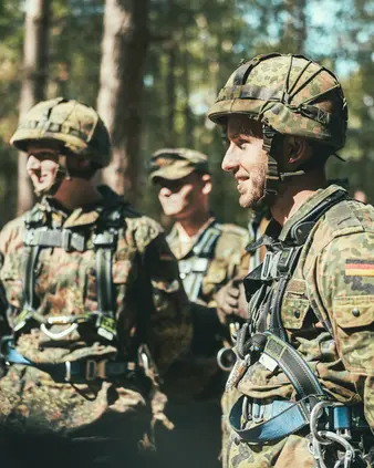Eine Gruppe Soldaten in Tarnkleidung steht in einem Wald