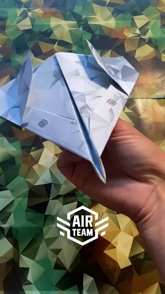 Ein Papierflieger wird von einer Person dargestellt. Das Air Team Logo ist unten im Bild zu sehen.