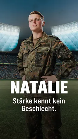 Natalie steht in Tarnkleidung auf einem Spielfeld im Fussballstadion
