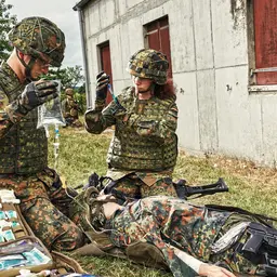 Soldatin und Soldat des Sanitätdienstes versorgen einen auf dem Boden liegenden Verwundeten