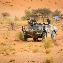 Ein gepanzertes Bundeswehrfahrzeug mit Antennen und Maschinengewehr steht im Gelände