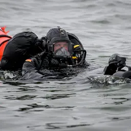 Ein Pioniertaucher mit Boje und weiterer Ausrüstung im Wasser