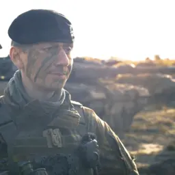 Soldat der Panzertruppe steht vor einem Panzer im Gelände