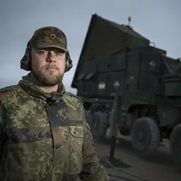 Soldat im Flugabwehrraketendienst steht vor einem großen LKW