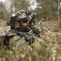 Soldaten liegen im Wald und sichern die Umgebung.