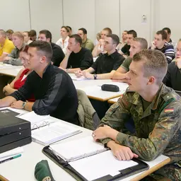Studenten in Uniform und zivil lauschen einer Vorlesung