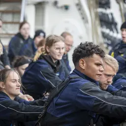 Jugendliche ziehen an Seilen an einem Schiff