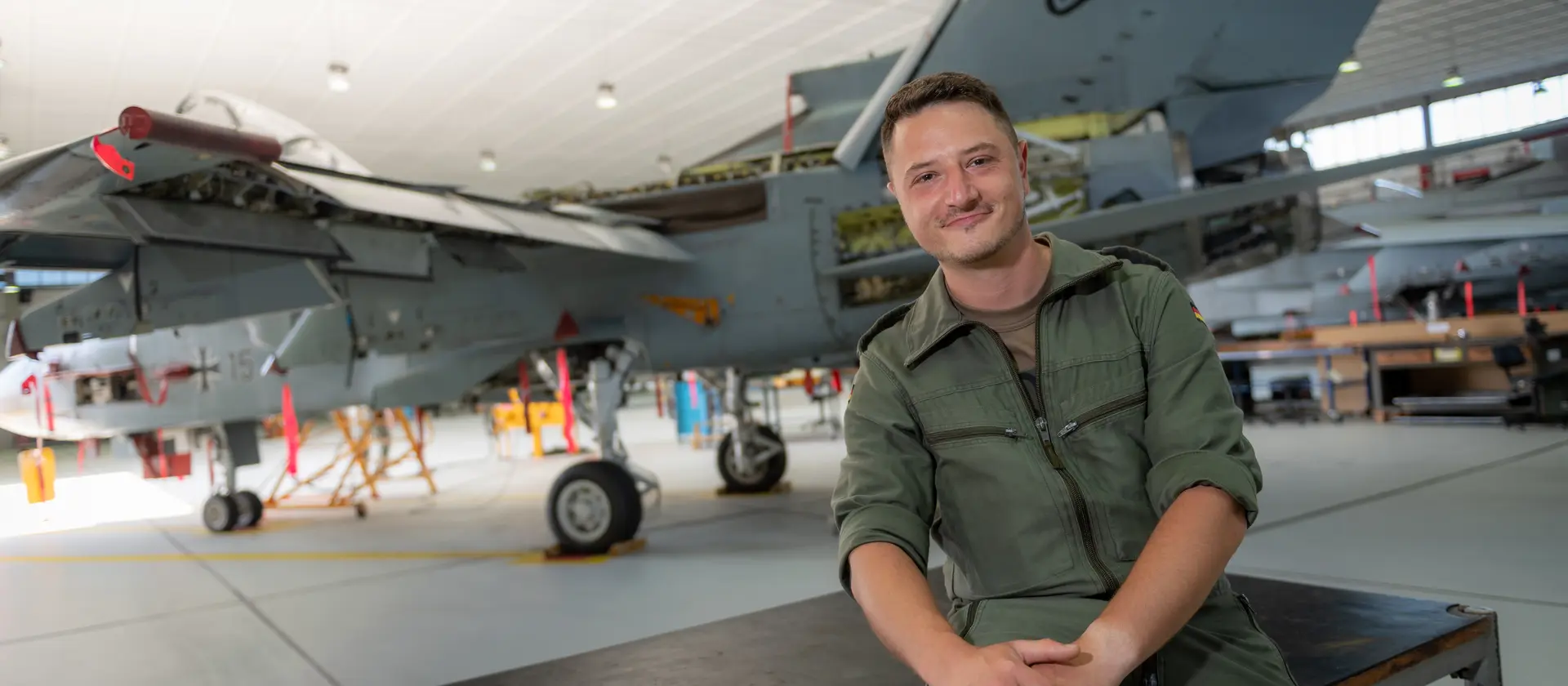 Ein Fluggerätmechaniker sitzt vor einem Kampfjet der Bundeswehr