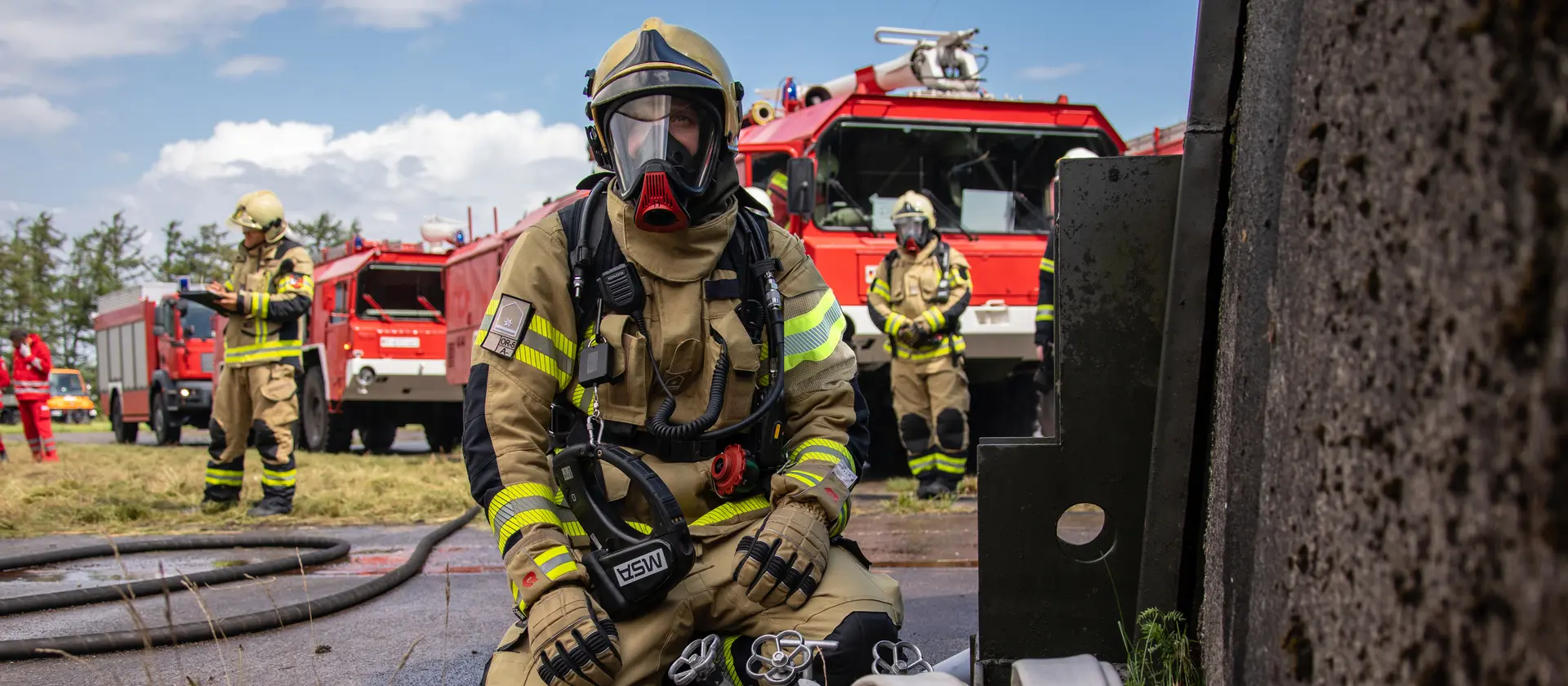 Ein Feuerwehrmann kniet vor einem Feuerwehrfahrzeug