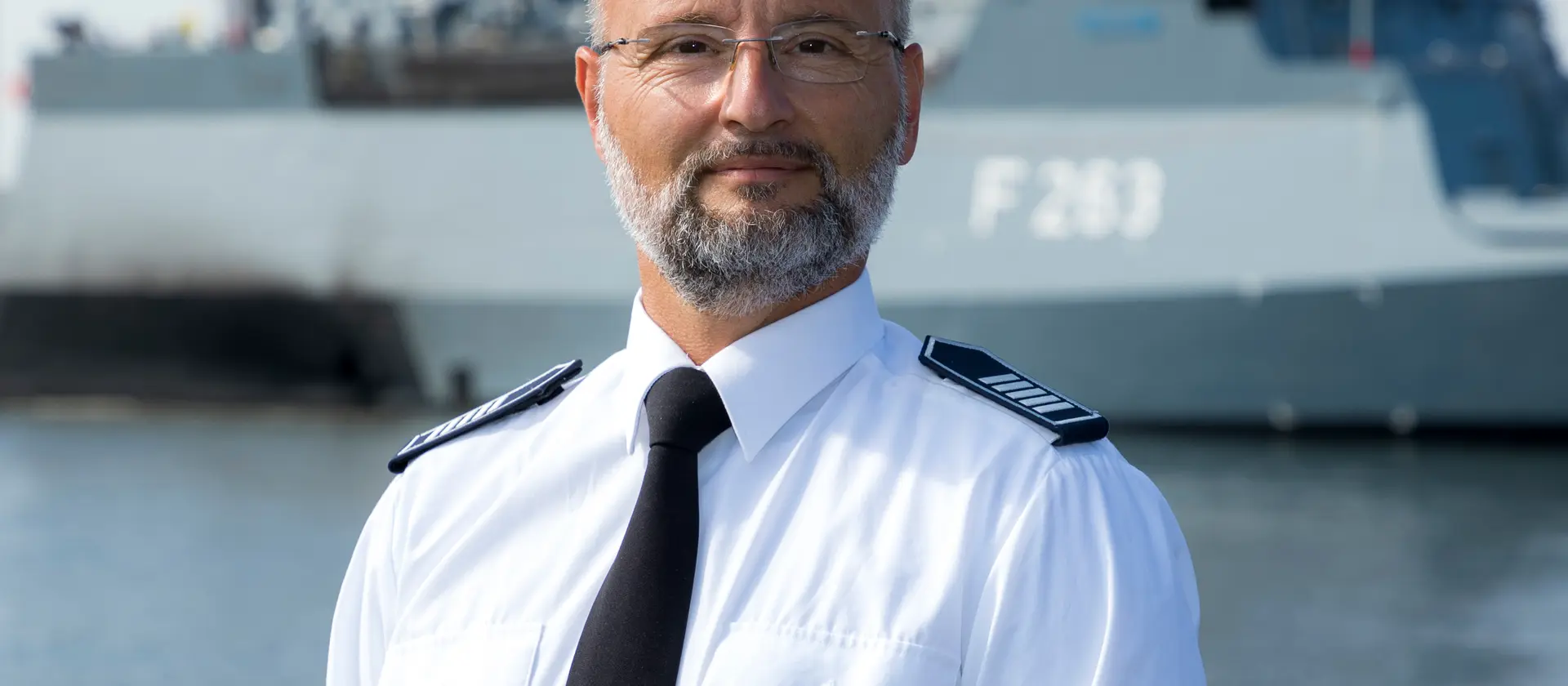 Der Leiter der Feuerwehr Warnemünde in Uniform vor einem Schiff