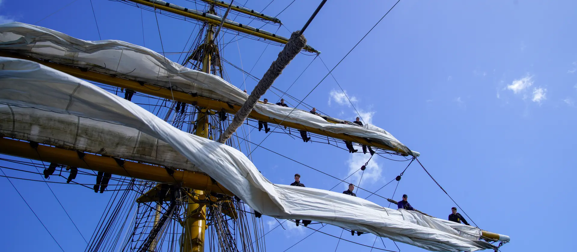 Menschen stehen auf einem Segel eines Schiffes