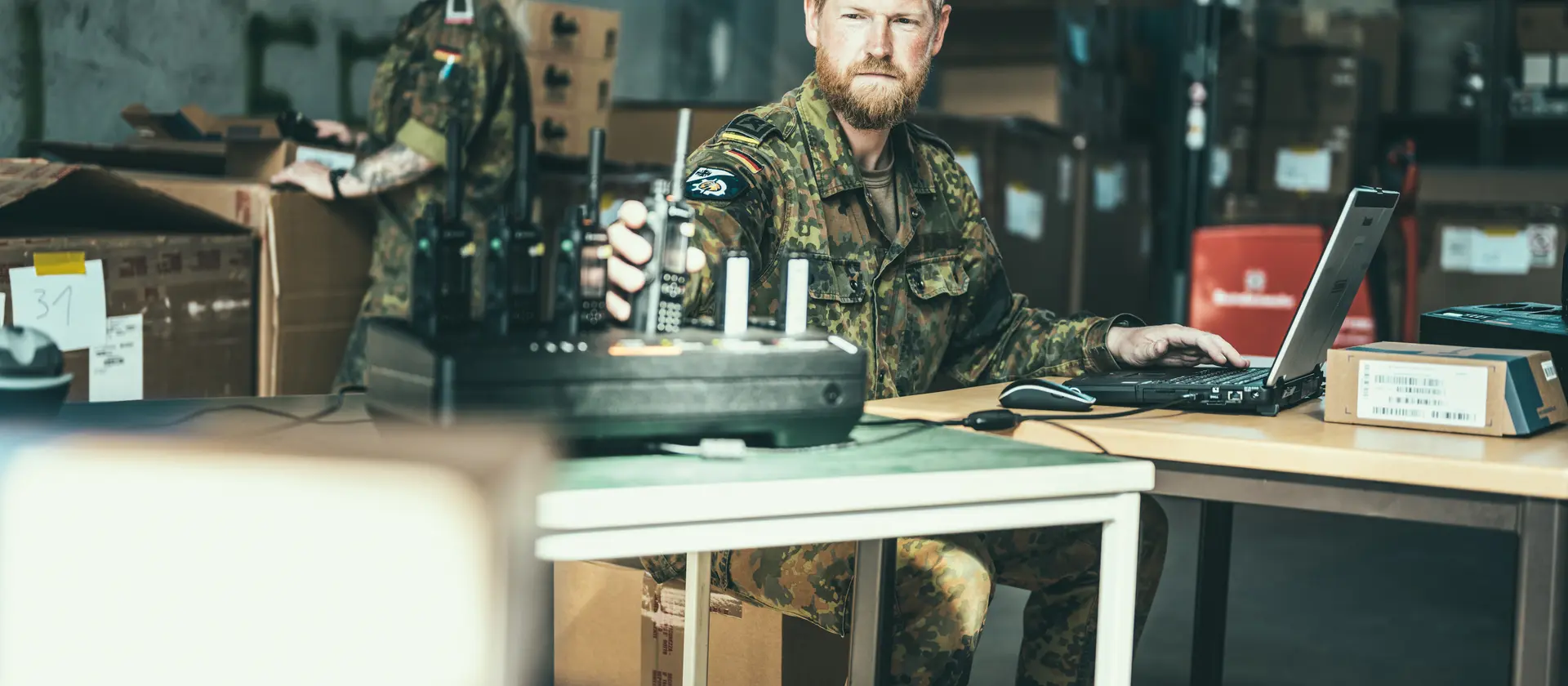 IT-Soldat sitzt vor Laptop und Funkgeräten