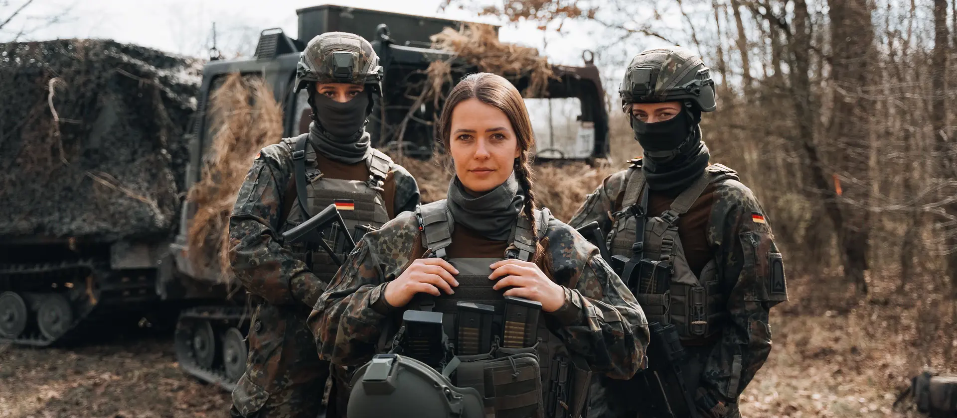3 Soldatinnen der Bundeswehr stehen vor einem Fahrzeug in einem Waldstück