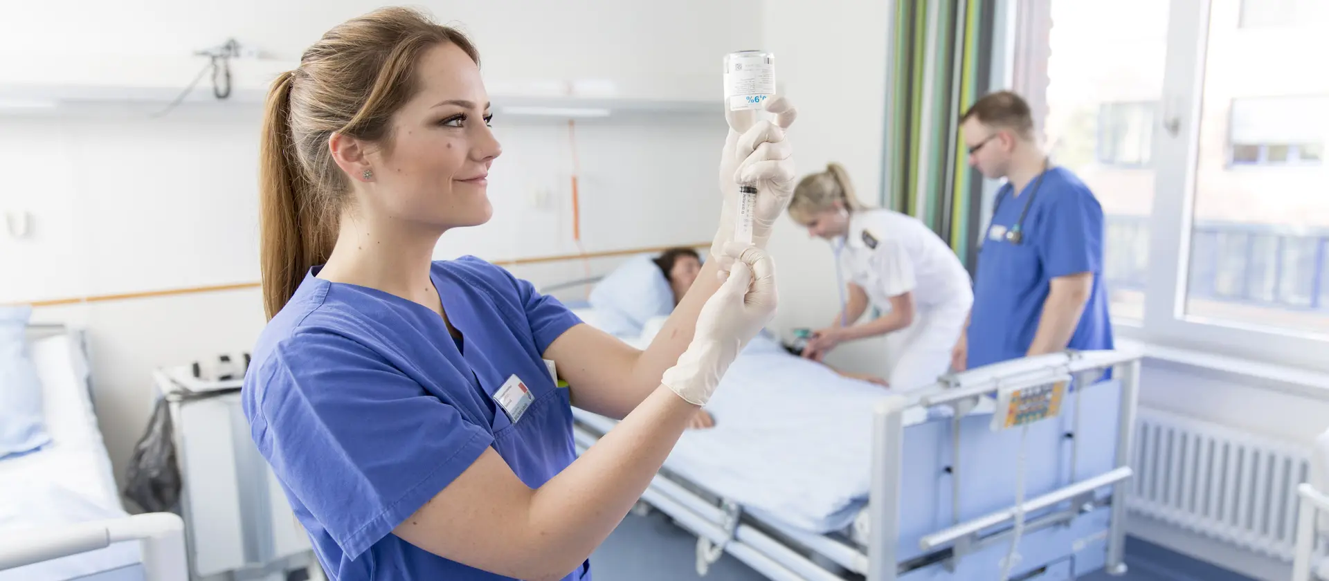 Pflegekräfte versorgen eine Patientin in einem Krankenzimmer