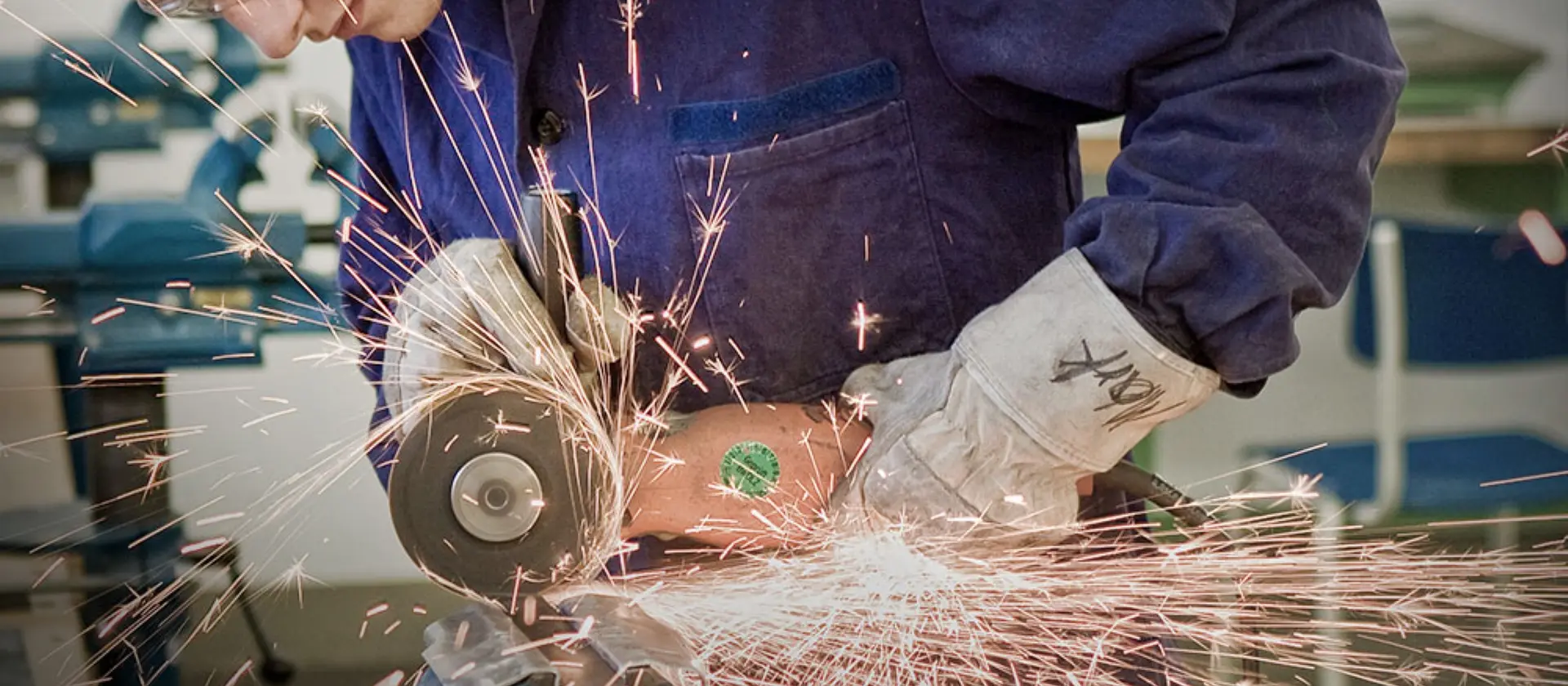Konstruktionsmechaniker mit Schutzbrille und Winkelschleifer bei der Arbeit