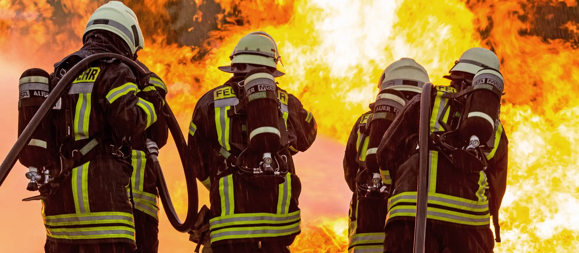 Vier Feuerwehrleute mit Atemschutzgeräten löschen einen Brand