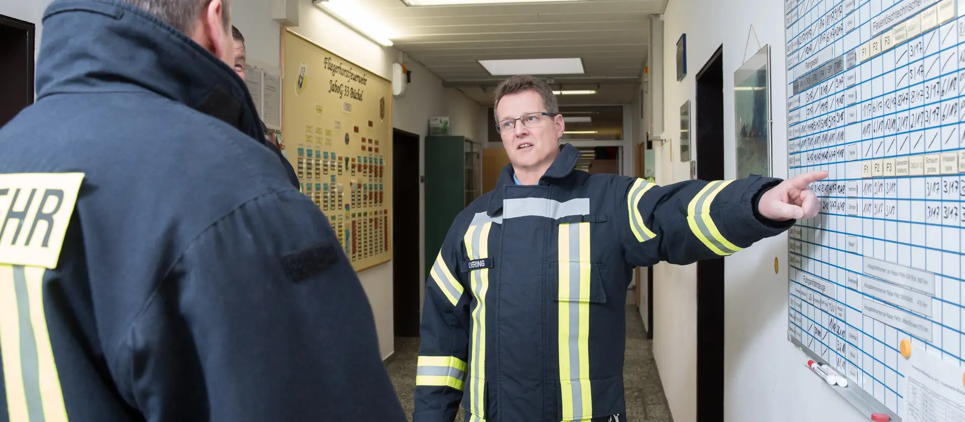 Feuerwehrmann zeigt auf einen Einsatzplan und bespricht sich mit einem Kollegen