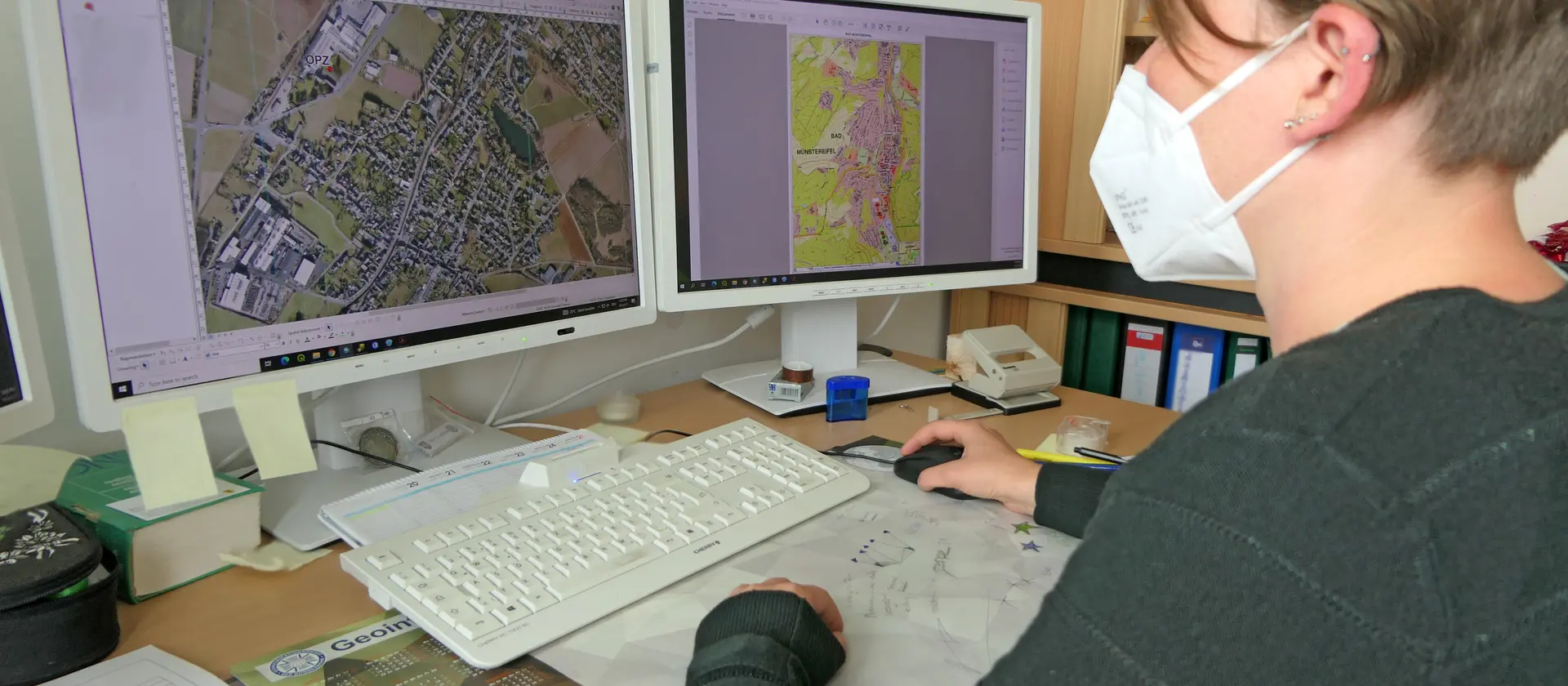 Eine Frau mit FFP-2 Maske schaut auf einen Monitor
